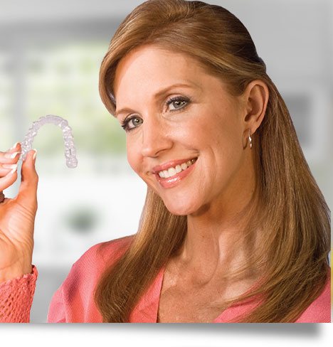 Woman holding a clear Invisalign aligner